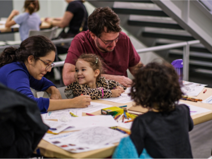 A family happily draws together at a coloring station.