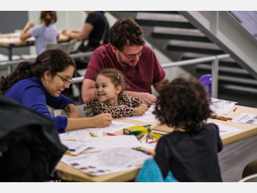 A family happily draws together at a coloring station.