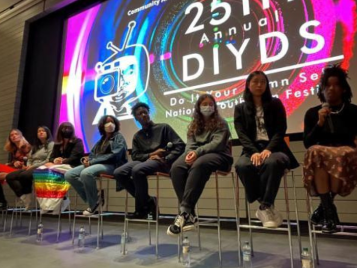 A photograph of young people on stage in front of a large screen that reads “25th Annual DIYDS.”