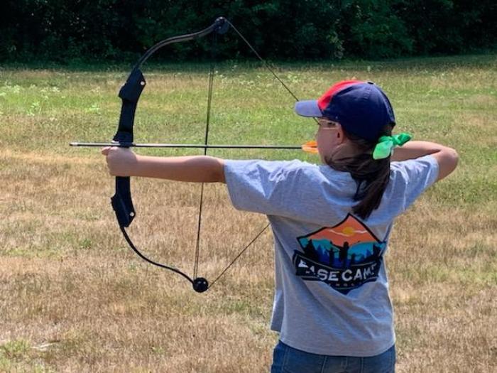 Photo of a camper shooting a bow and arrow.