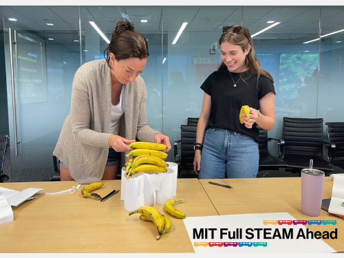 Two teachers constructing a structure to hold a pile of bananas.